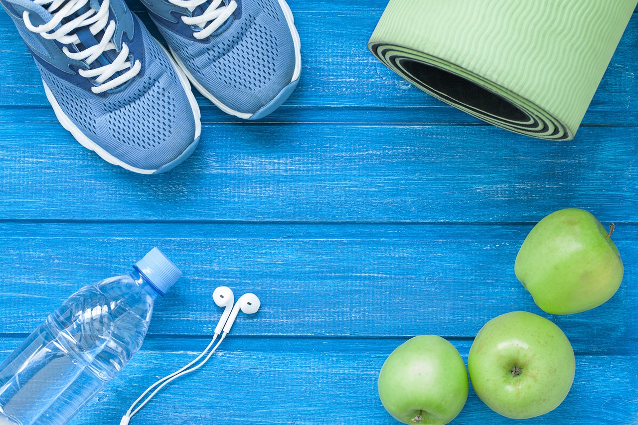 flat lay sport shoes bottle of water mat and earphones